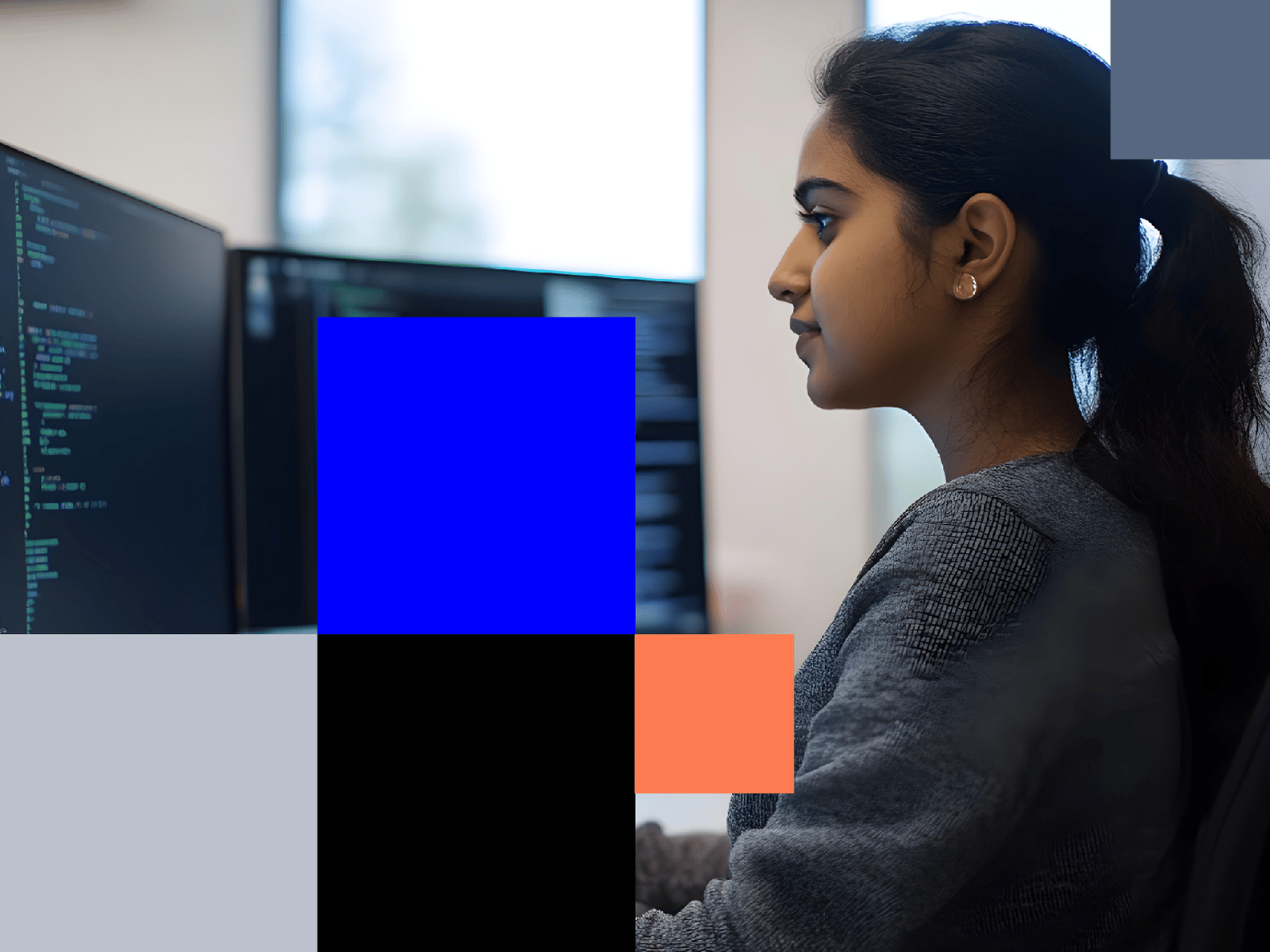 A woman with dark hair in a ponytail looks at a computer screen